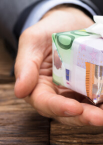 Adobe Stock: Businessman Holding Gift Box Made From Euro Papernotes Von Andrey Popov 